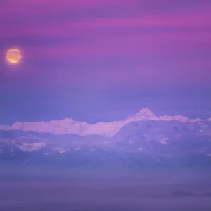 Coucher de soleil violet sur montagnes enneigées avec pleine lune