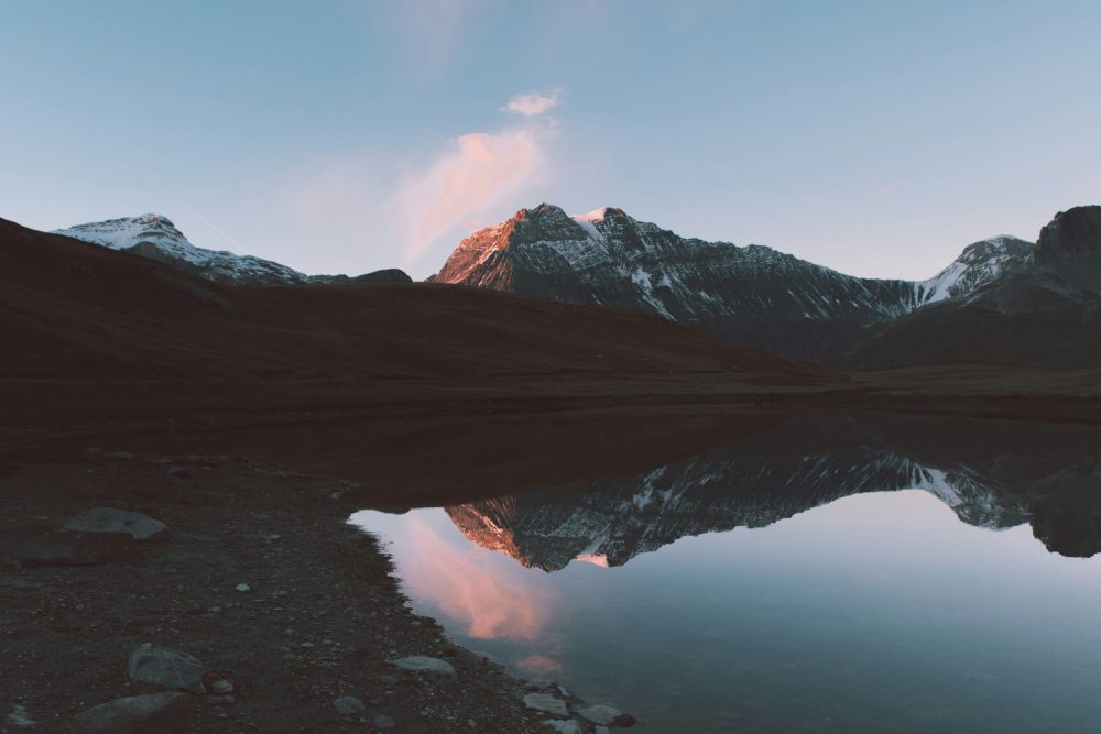 Reflet montagneux au coucher de soleil dans lac tranquille
