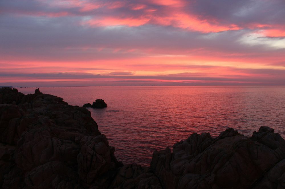 Coucher de soleil romantique sur côte rocheuse aux nuances roses