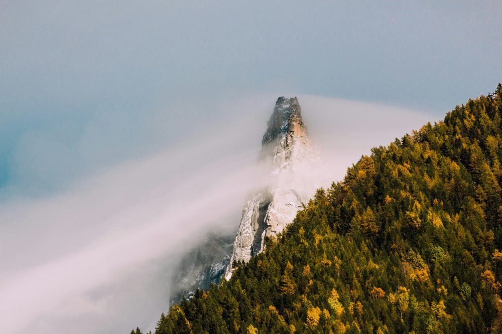 Sommet rocheux dans les nuages avec forêt dorée automnale